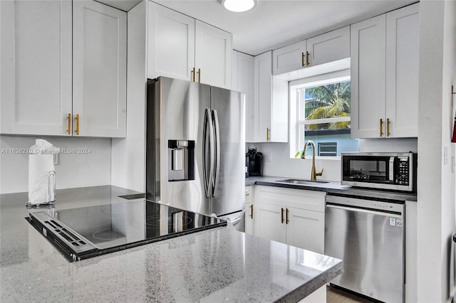 kitchen featuring appliances with stainless steel finishes, dark stone countertops, white cabinets, and sink