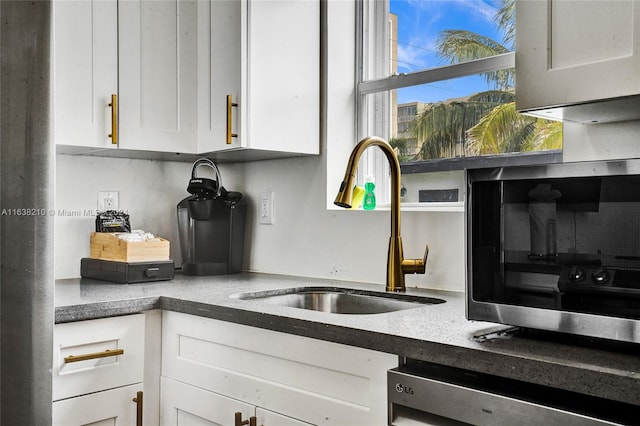 kitchen featuring sink, dishwasher, and white cabinets