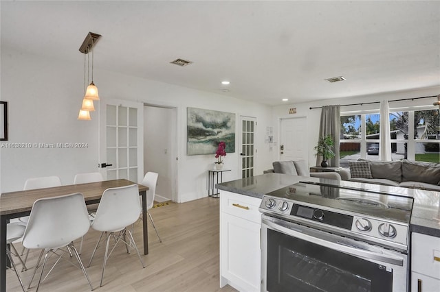 kitchen with dark stone counters, white cabinetry, light wood-type flooring, and stainless steel electric range oven