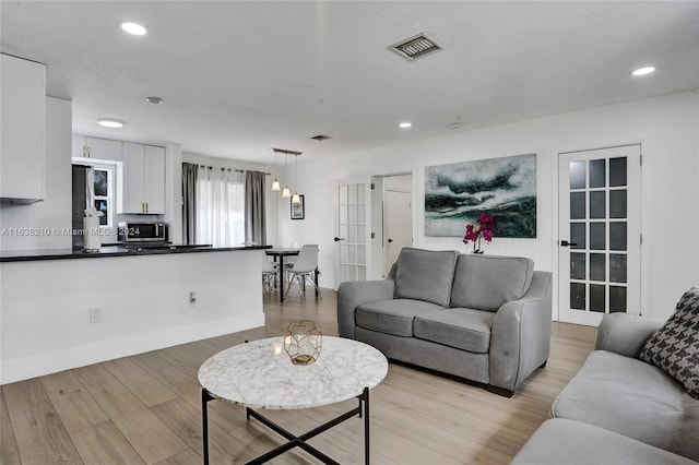 living room featuring french doors and light hardwood / wood-style flooring