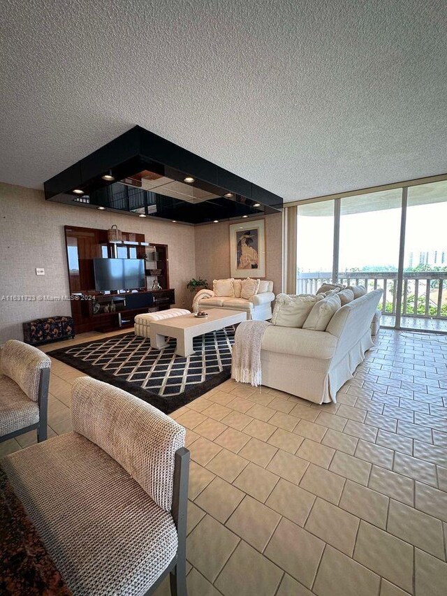 living room with a textured ceiling, a wall of windows, and tile patterned floors