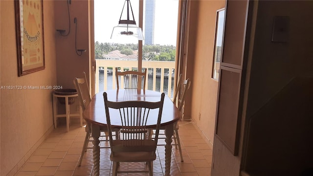 dining space featuring a water view and light tile patterned floors