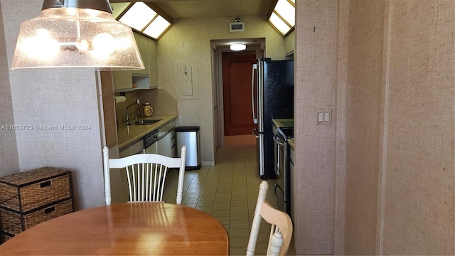 kitchen with light tile patterned floors, lofted ceiling, a sink, visible vents, and freestanding refrigerator