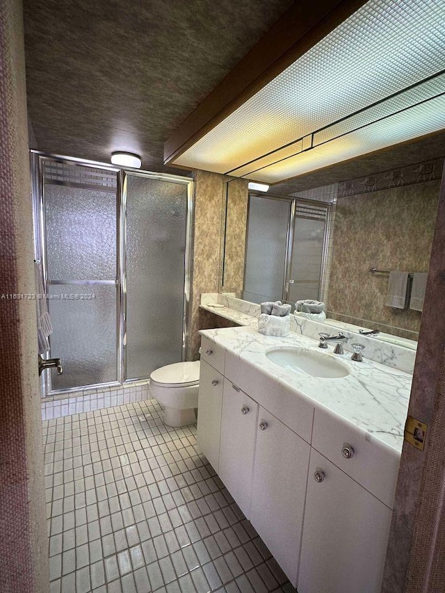 full bath featuring a stall shower, vanity, toilet, and tile patterned floors