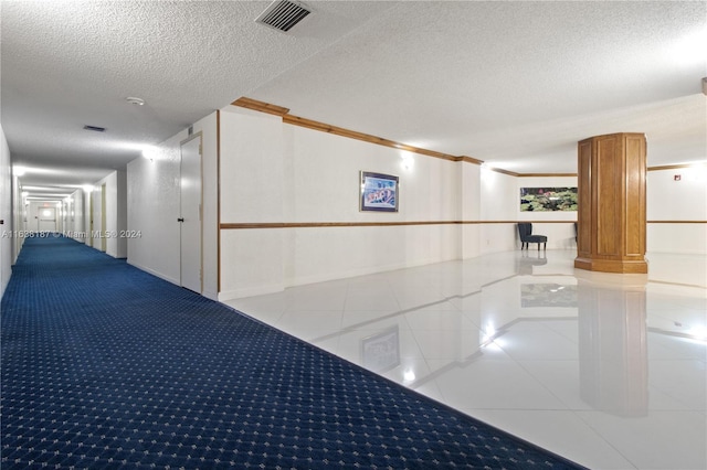 hallway featuring a textured ceiling, crown molding, and light tile patterned floors