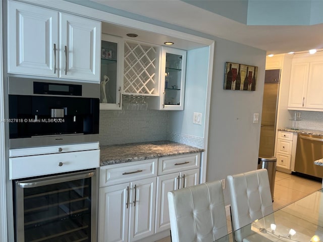 kitchen featuring stainless steel appliances, white cabinetry, light tile patterned floors, tasteful backsplash, and beverage cooler