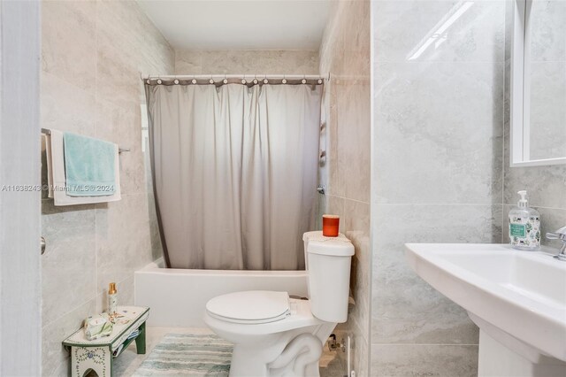 full bathroom with shower / tub combo with curtain, tile walls, toilet, and sink