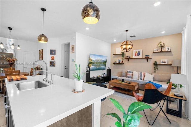 kitchen with a notable chandelier, pendant lighting, sink, a center island with sink, and light tile patterned floors