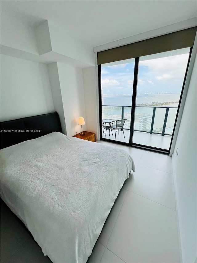 tiled bedroom featuring a wall of windows, access to exterior, and a water view