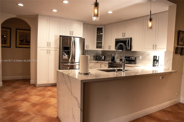 kitchen featuring tasteful backsplash, stainless steel appliances, white cabinets, pendant lighting, and kitchen peninsula