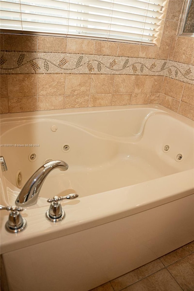 bathroom with a washtub, a wealth of natural light, and tile patterned flooring