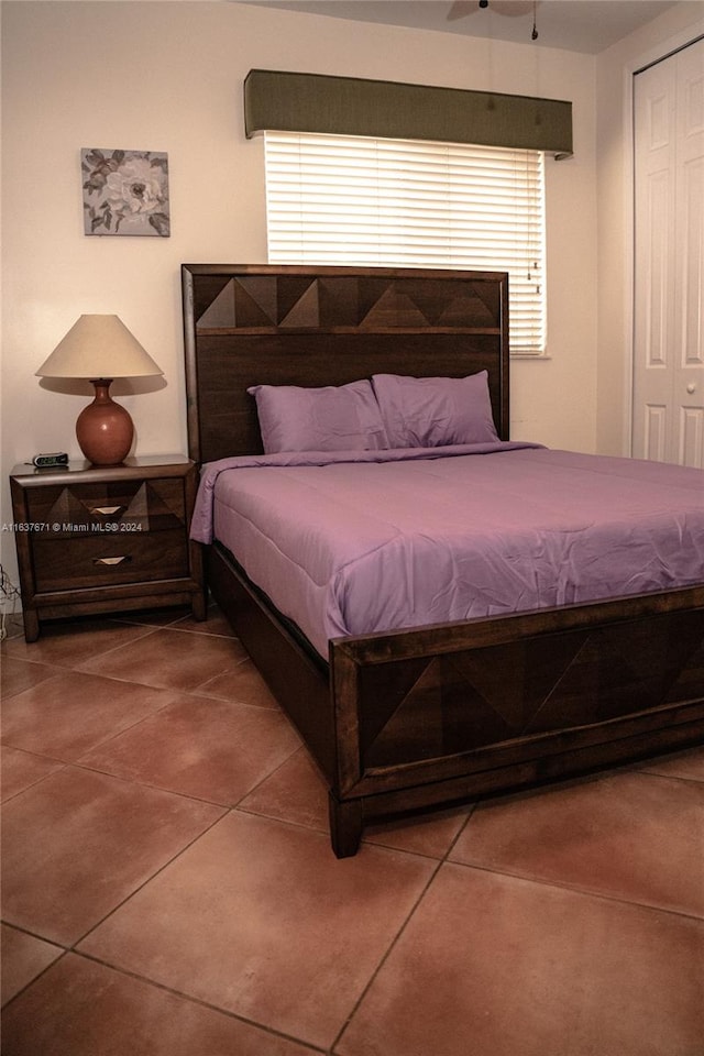 tiled bedroom featuring ceiling fan and a closet