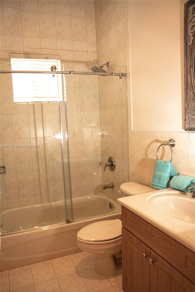 full bathroom with tile walls, tile patterned floors, shower / bath combination with glass door, and vanity