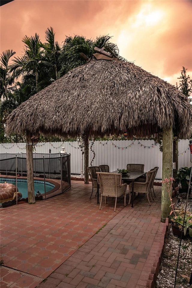 patio terrace at dusk featuring a fenced in pool and a gazebo