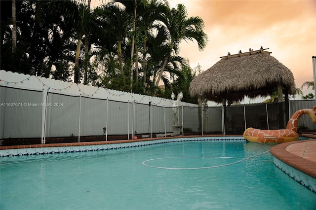 pool at dusk featuring a gazebo