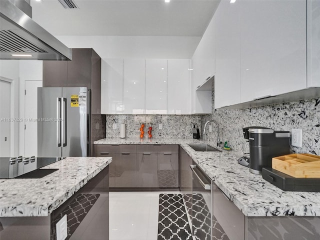 kitchen featuring sink, white cabinetry, light stone countertops, stainless steel appliances, and range hood