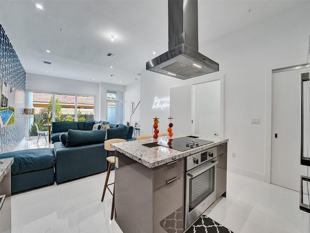 kitchen with a kitchen island, a breakfast bar, island exhaust hood, black electric stovetop, and stainless steel oven