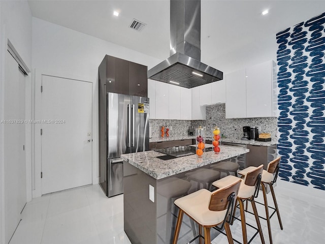 kitchen with a breakfast bar area, a center island, black electric stovetop, island range hood, and white cabinets