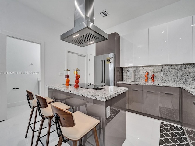 kitchen featuring island range hood, white cabinetry, a breakfast bar area, high end refrigerator, and light stone countertops