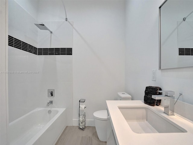 full bathroom featuring vanity, tiled shower / bath, and toilet