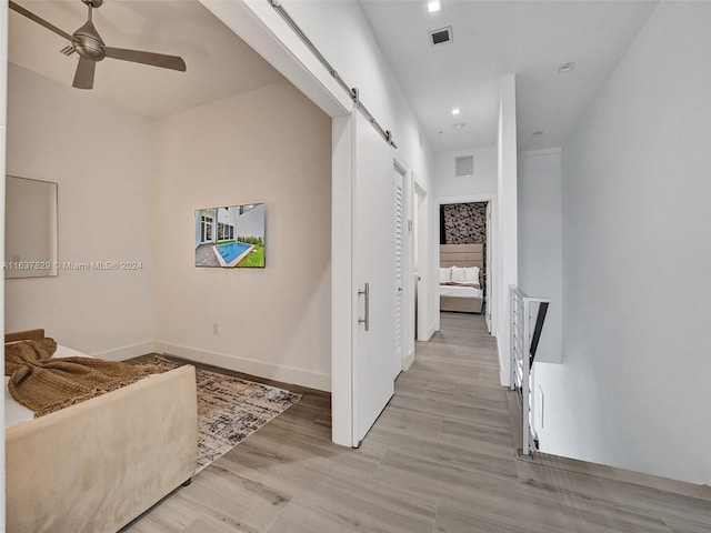 hallway with light hardwood / wood-style flooring and a barn door