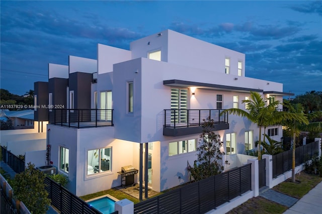 property exterior at dusk featuring a balcony