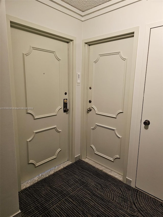 doorway to outside with a textured ceiling and dark carpet