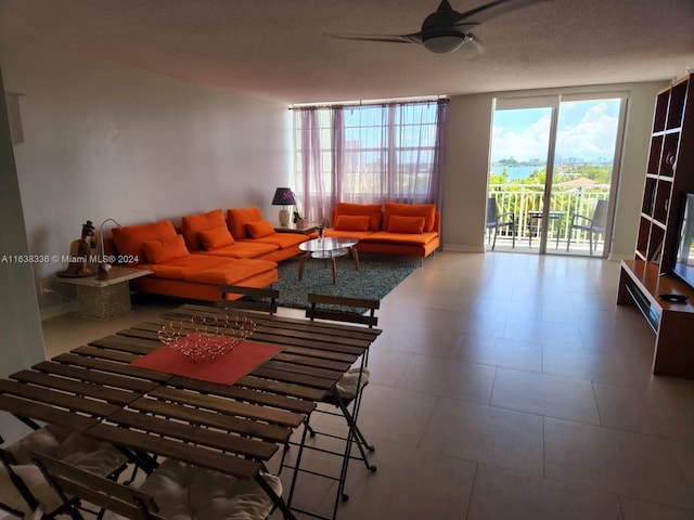 living room with ceiling fan, a textured ceiling, and floor to ceiling windows