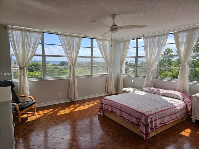 bedroom with ceiling fan, multiple windows, and a textured ceiling