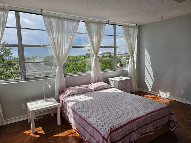 bedroom featuring multiple windows, a textured ceiling, a water view, and dark parquet floors