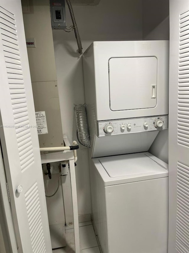 laundry room featuring stacked washer and clothes dryer and tile patterned flooring