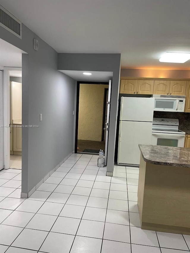 kitchen with light brown cabinetry, white appliances, and light tile patterned floors