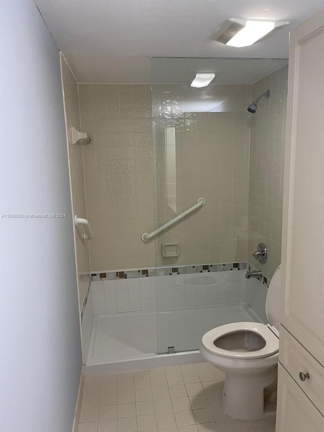 bathroom with a tile shower, tile patterned flooring, and toilet