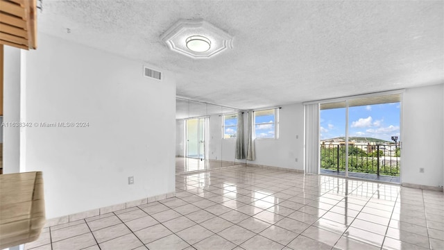 spare room featuring expansive windows, light tile patterned floors, and a textured ceiling