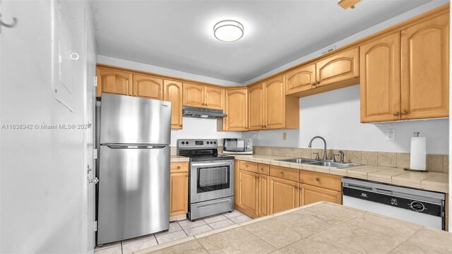 kitchen featuring tile countertops, light tile patterned flooring, sink, and appliances with stainless steel finishes