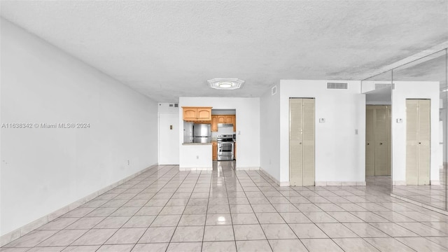 unfurnished living room with a textured ceiling and light tile patterned flooring