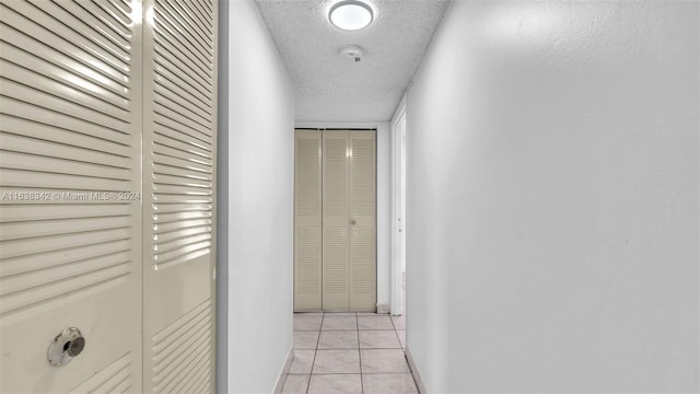 corridor with light tile patterned floors and a textured ceiling