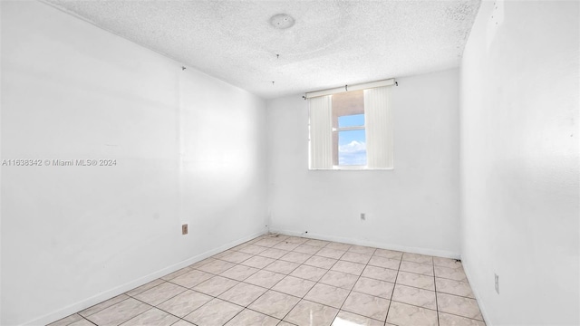 empty room with light tile patterned flooring and a textured ceiling