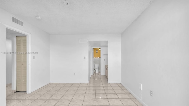 empty room featuring light tile patterned floors and a textured ceiling