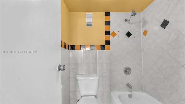 bathroom featuring toilet and tiled shower / bath