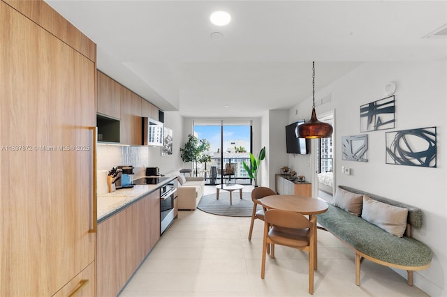 kitchen with light tile patterned flooring, tasteful backsplash, range, decorative light fixtures, and light stone countertops