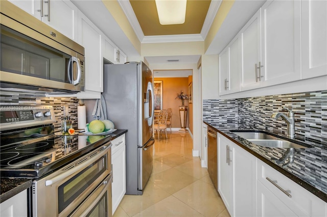 kitchen with appliances with stainless steel finishes, sink, backsplash, dark stone countertops, and white cabinetry