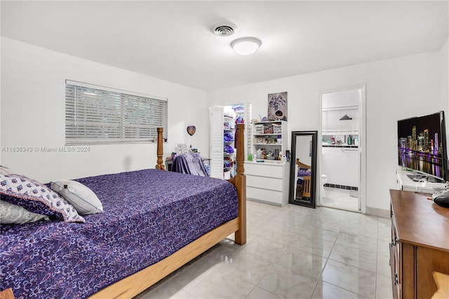 bedroom with connected bathroom and light tile patterned floors