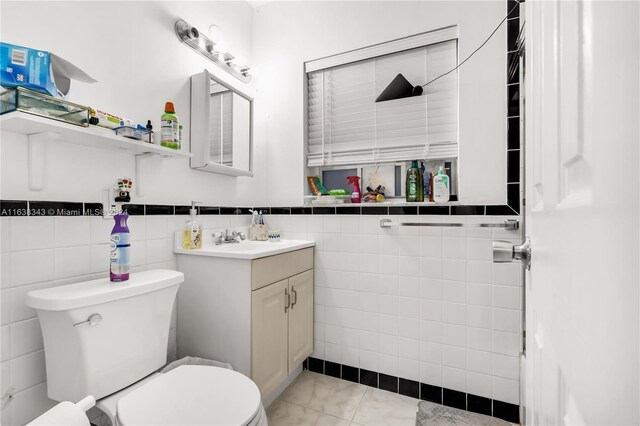 bathroom with tile patterned flooring, tile walls, toilet, and vanity