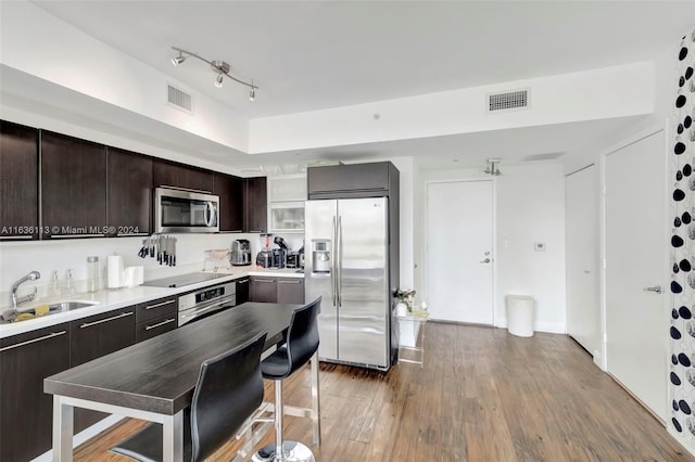 kitchen with visible vents, a sink, dark brown cabinets, light wood-style floors, and appliances with stainless steel finishes