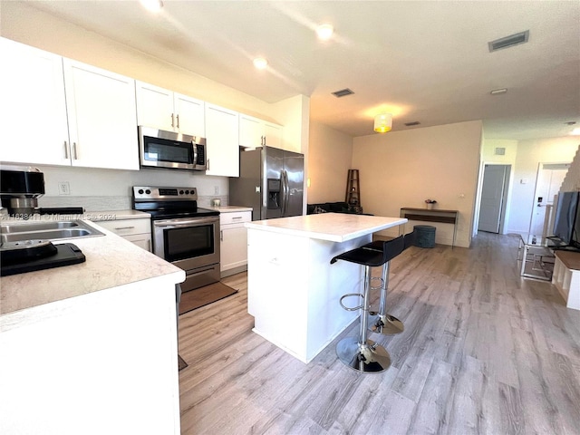 kitchen featuring sink, white cabinetry, light hardwood / wood-style flooring, a kitchen island, and stainless steel appliances