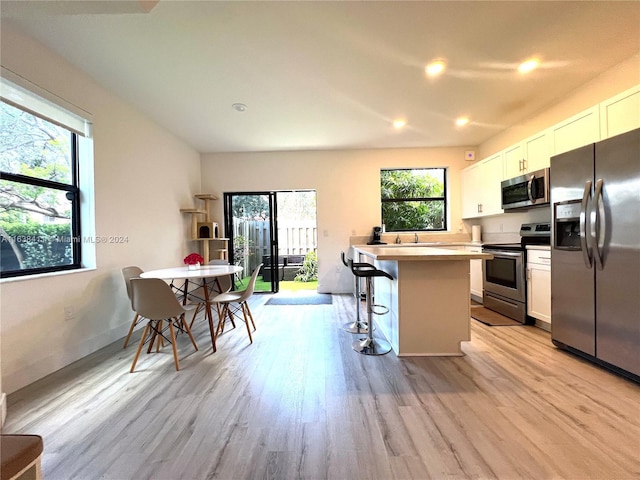 kitchen featuring white cabinetry, stainless steel appliances, a center island, and a kitchen bar