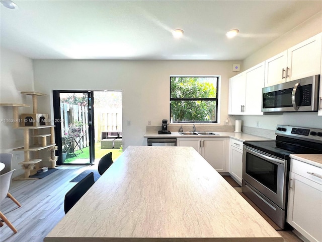 kitchen featuring white cabinetry, appliances with stainless steel finishes, sink, and wood-type flooring