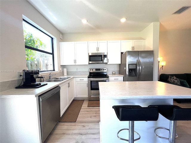 kitchen featuring stainless steel appliances, sink, white cabinets, and light hardwood / wood-style flooring