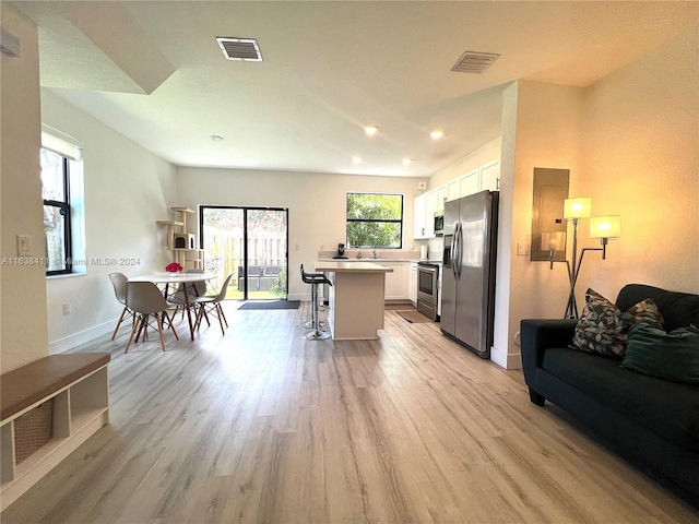 kitchen featuring light hardwood / wood-style flooring, a kitchen breakfast bar, a kitchen island, stainless steel appliances, and white cabinets